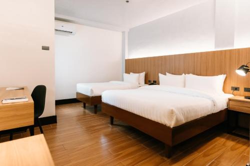 a hotel room with two beds and a desk at El Sancho Hotel in Naga