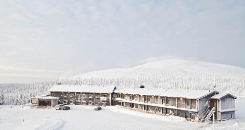 a lodge in the snow with a mountain in the background at Lapland Hotels Pallas in Pallastunturi