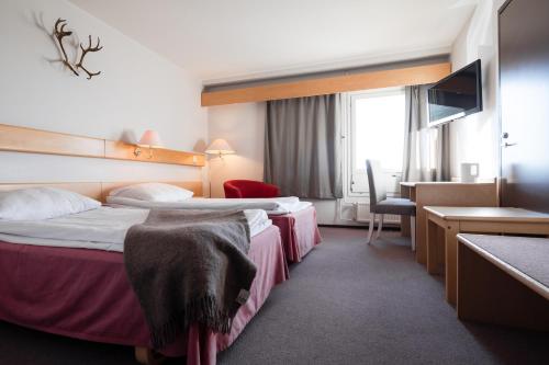 a hotel room with two beds and a desk at Lapland Hotels Pallas in Pallastunturi