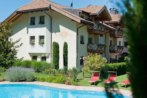 una casa con piscina y sillas rojas en Residence Werth, en Bolzano