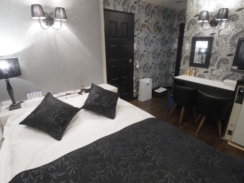 a bedroom with a bed with black pillows and a sink at SKYROAD Adult Only in Tokyo