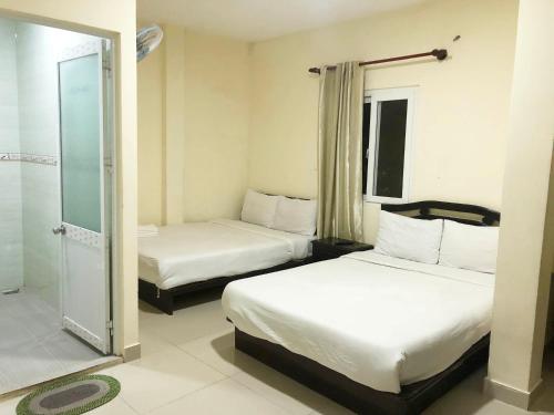 a hotel room with two beds and a shower at Phuong Hong Guesthouse in Da Lat