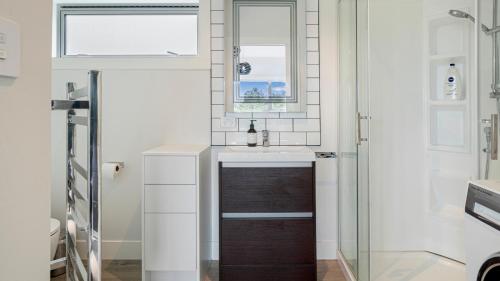 a bathroom with a sink and a mirror at Pohutukawa Paradise - Martins Bay Holiday Home in Mullet Point