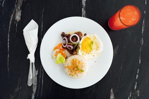 a plate of food with eggs and vegetables on a table at El Sancho Hotel in Naga