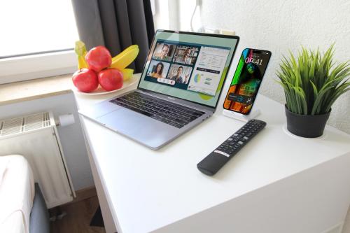 a laptop computer sitting on a desk with a remote control at Downtown Apartments Ulm - im Herzen von Ulm & komfortable Boxspringbetten in Ulm