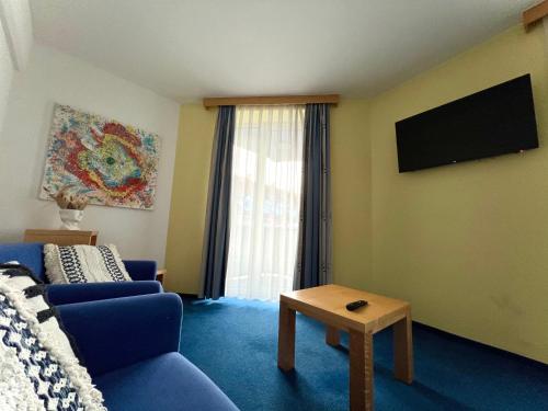 a living room with a blue couch and a tv at Hotel Jeruzalem in Ljutomer