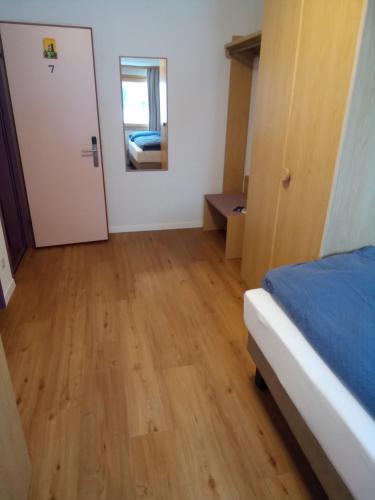 a bedroom with a bed and a door and a wooden floor at Alpenlodge Kühboden in Fiesch