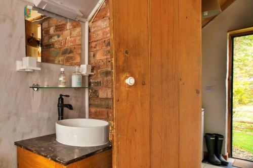a bathroom with a sink and a brick wall at Finest Retreats - Great Cantal Granary in Llandrindod Wells