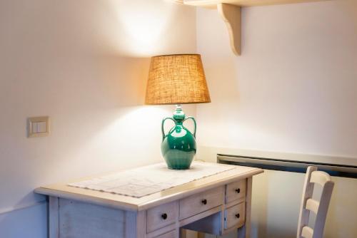 a green vase on a table with a lamp on it at Agriturismo Arco di Sole in Alberobello