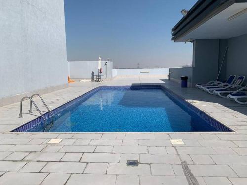 - une piscine avec des chaises à côté d'un bâtiment dans l'établissement A Calm&Cozy 1BR-20 MIN-DXB AIRPT, à Dubaï