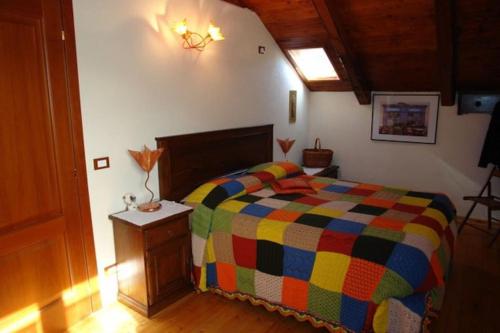 a bedroom with a colorful bed and a wooden floor at Bonne Ville in Cesana Torinese