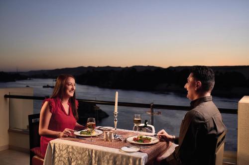 a man and a woman sitting at a table with food at Mövenpick Resort Aswan in Aswan