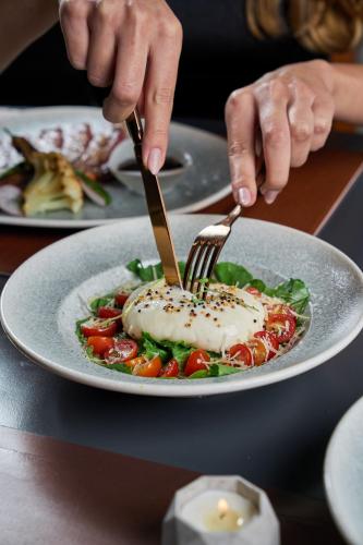 a person eating a plate of food with fork and knife at Radisson Blu Hotel, Cairo Heliopolis in Cairo
