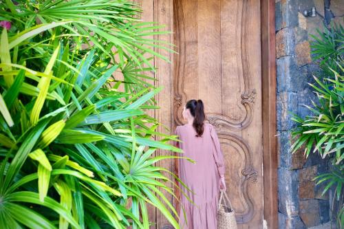 a woman standing in front of a door in front of a fence at Hôtel 20 Degrés Sud - Relais & Châteaux in Grand Baie