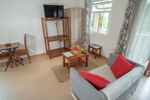 a living room with a couch and a table at La Maison Hibiscus Self Catering Accommodation in Beau Vallon