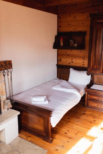 a bedroom with a wooden bed with white sheets at ETNO SELO VRANEŠA Zlatar in Nova Varoš