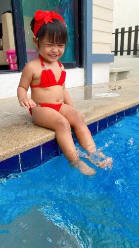a young girl in a red bikini sitting next to a swimming pool at Sweet Party Hua-Hin Private Poolvilla From beach 3km in Hua Hin