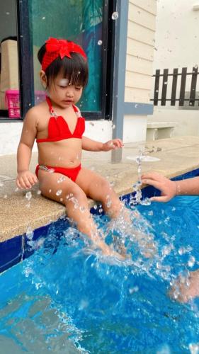 a little girl in a red bikini sitting in a swimming pool at Sweet Party Hua-Hin Private Poolvilla From beach 3km in Hua Hin