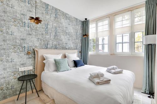 une chambre avec un grand lit blanc avec des serviettes dessus dans l'établissement Pick A Flat's Apartment near place de la Bastille - Rue du Faubourg Saint Antoine, à Paris