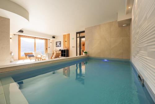 a swimming pool with blue water in a house at CHALET LA MANIGODINE Piscine 18-24 pers in Manigod