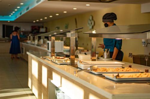 una linea a buffet in un ristorante con persone che preparano il cibo di Apartamentos Playa Moreia a S'Illot
