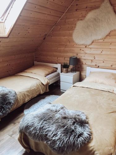 two beds in a room with wooden walls at Domki Nad Potokiem574067621 in Ustrzyki Dolne