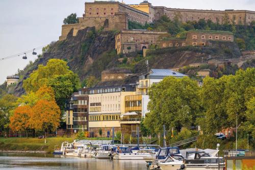 a bunch of boats docked in a river with a castle at Diehls Hotel in Koblenz