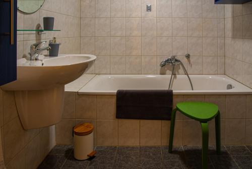 La salle de bains est pourvue d'un lavabo, d'une baignoire et d'un tabouret vert. dans l'établissement Kanaalzicht21, à Hasselt