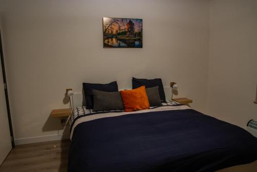 um quarto com uma cama azul com almofadas laranja em Kanaalzicht21 em Hasselt