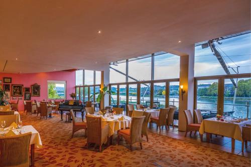 a restaurant with tables and chairs and large windows at Diehls Hotel in Koblenz