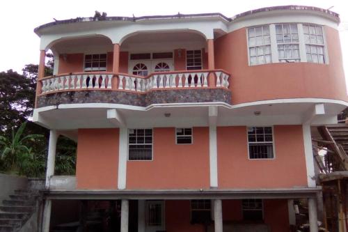 a pink building with a balcony on top of it at Home Style Apartment J in Roseau