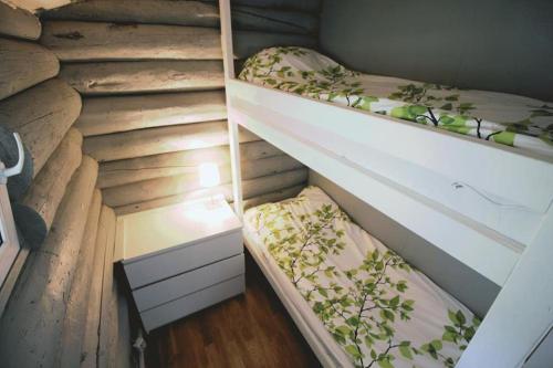 two empty bunk beds in a room with wooden floors at Beautiful riverside cottage with sauna in Nuorgam