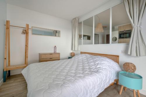 une chambre avec un lit blanc et une chaise bleue dans l'établissement Charmant appartement vue mer!, à La Baule