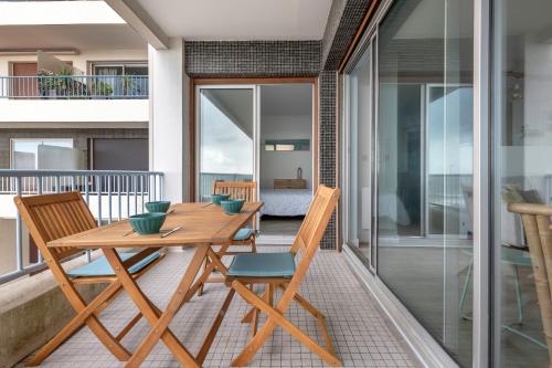 une table et des chaises en bois sur un balcon dans l'établissement Charmant appartement vue mer!, à La Baule