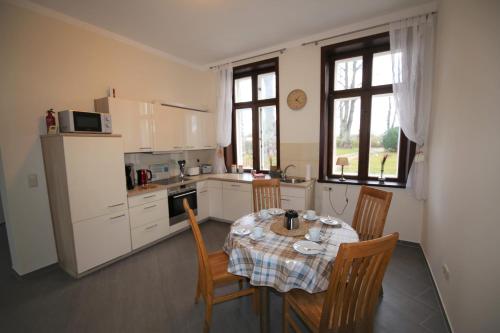 una cocina con mesa y sillas y una cocina con armarios blancos. en Herrenhaus Hohewarte, en Lübeck