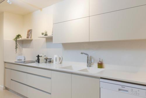 eine weiße Küche mit weißen Schränken und einem Waschbecken in der Unterkunft The Pearl of Nachlaot Apartments in Jerusalem