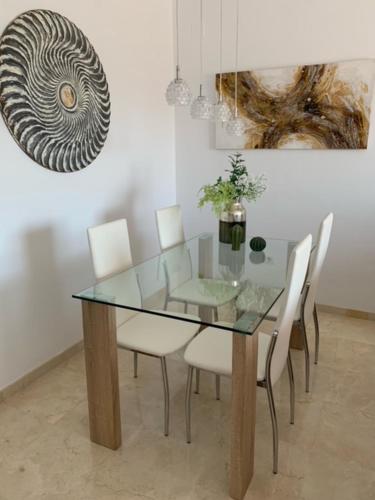 uma sala de jantar com uma mesa de vidro e cadeiras brancas em Casa Elsi Prachtig vernieuwd appartement em Manilva