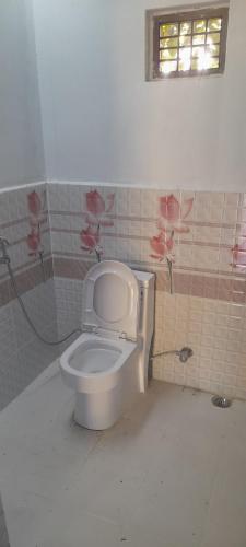 a bathroom with a toilet with pink flowers on the wall at Good Karma Homestay in Bhurkīā