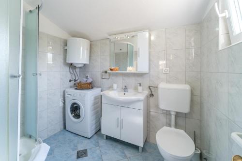 a white bathroom with a washing machine and a sink at Holiday Home Gabelot in Supetar