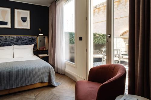 sypialnia z łóżkiem, krzesłem i oknem w obiekcie The Cumberland Hotel by NEU Collective w mieście Valletta