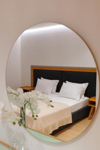 a mirror reflecting a bed with white pillows at Hotel Nertili in Sarandë