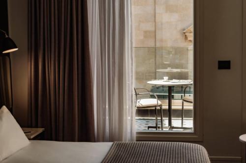 a room with a bed and a window with a table at The Cumberland by NEU Collective in Valletta