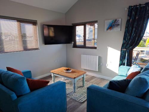 a living room with two blue couches and a table at River Bay - Norfolk Broads in Brundall