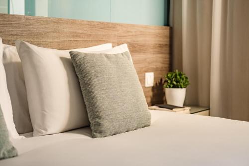 a bed with white pillows and a wooden headboard at 115 The Strand Hotel by NEU Collective in Il-Gżira