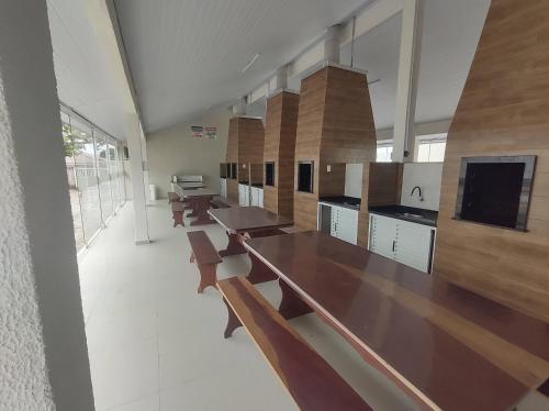 a large kitchen with wooden tables and benches at APTO TÉRREO a 50 Metros do MAR em Condomínio com PISCINAS MARAVILHOSAS in Guaratuba