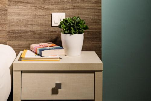 a table with a potted plant and books on it at 115 The Strand Hotel by NEU Collective in Il-Gżira