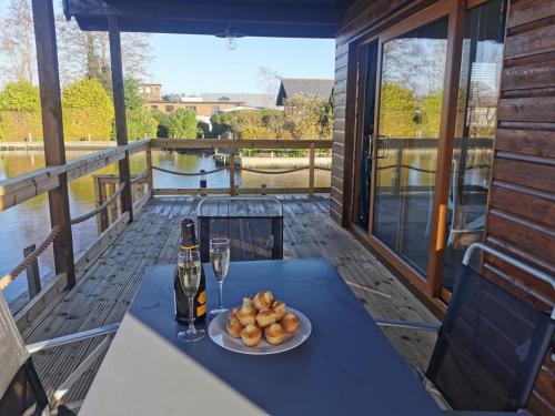a table with a bottle of wine and a plate of food at River Bay - Norfolk Broads in Brundall