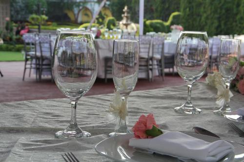 tres copas de vino sentadas en una mesa con un plato en Hotel La Villa Real, en Cuautla Morelos