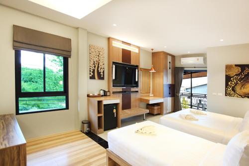 a hotel room with two beds and a television at Avarin Resort in Pak Chong