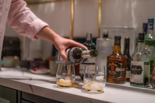 a person pouring a drink into two glasses on a counter at Villa Chez les Amis - Adults only in Balatonszepezd